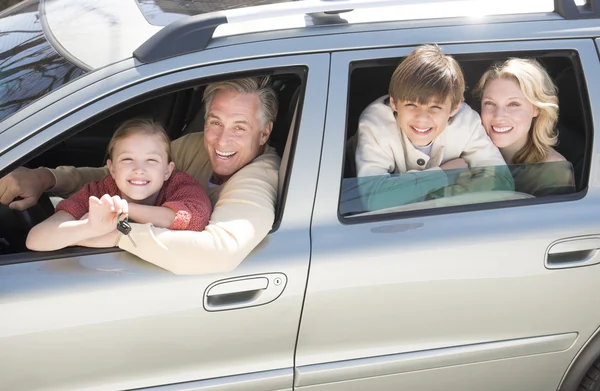 Fille montrant des clés de voiture tout en étant assis avec la famille dans la voiture — Photo