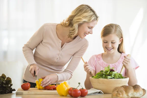 Mädchen unterstützt Mutter bei der Essenszubereitung an der Theke — Stockfoto