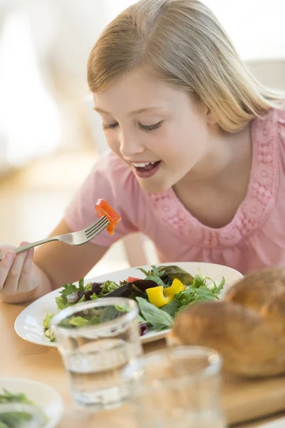 Dívka jíst salát na jídelní stůl — Stock fotografie