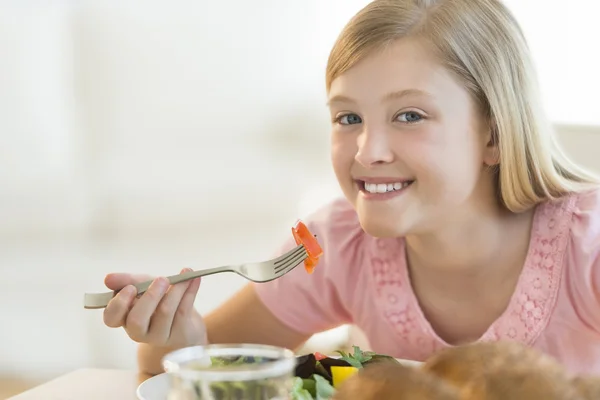 Glückliches Mädchen mit Salat am Esstisch — Stockfoto