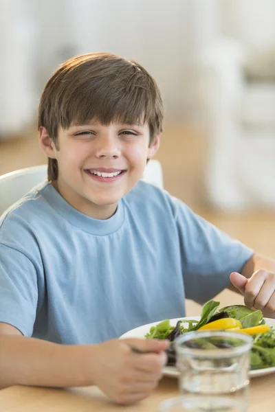 Chlapec s čerstvý salát na jídelní stůl — Stock fotografie