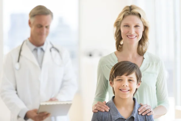 Mãe e filho com médico examinando relatório no fundo — Fotografia de Stock