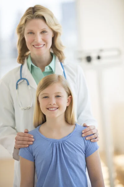 Médico confiante de pé com menina na clínica — Fotografia de Stock