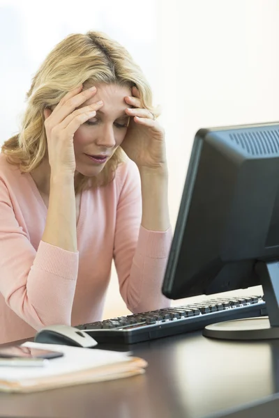 Geschäftsfrau mit Kopf in den Händen sitzt am Schreibtisch — Stockfoto