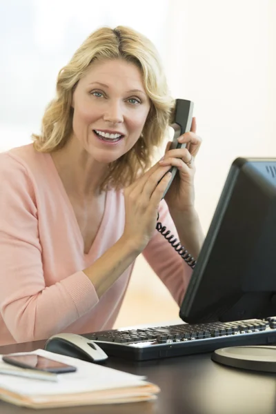 Businesswoman Covering Telephone Receiver At Desk — Stock Photo, Image