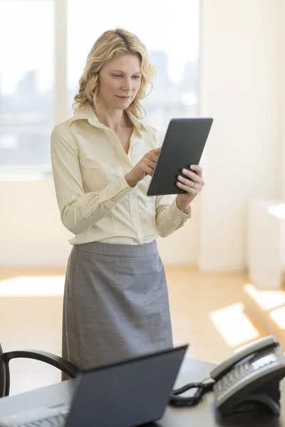 Zakenvrouw digitale Tablet PC terwijl staande via bureau — Stockfoto