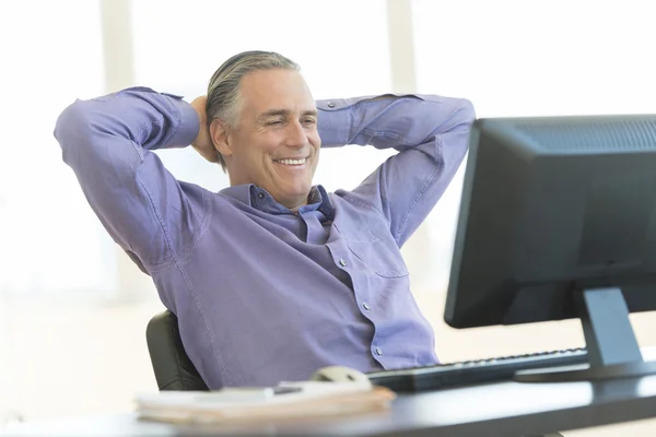 Empresario con las manos detrás de la cabeza mirando a la computadora en la oficina —  Fotos de Stock