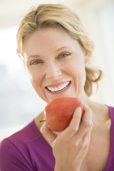 Mujer feliz sosteniendo manzana fresca en el gimnasio —  Fotos de Stock