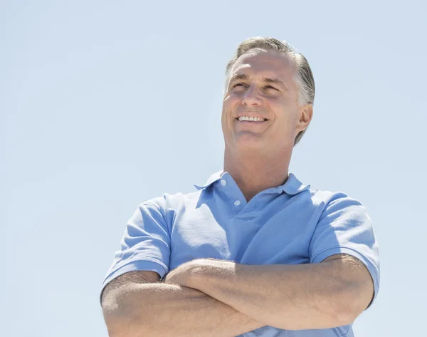 Man die weg met armen gekruist tegen heldere hemel — Stockfoto