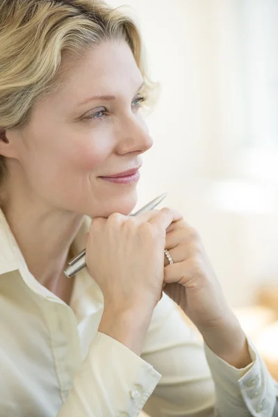 Affärskvinna med hand på hakan tittar bort i office — Stockfoto