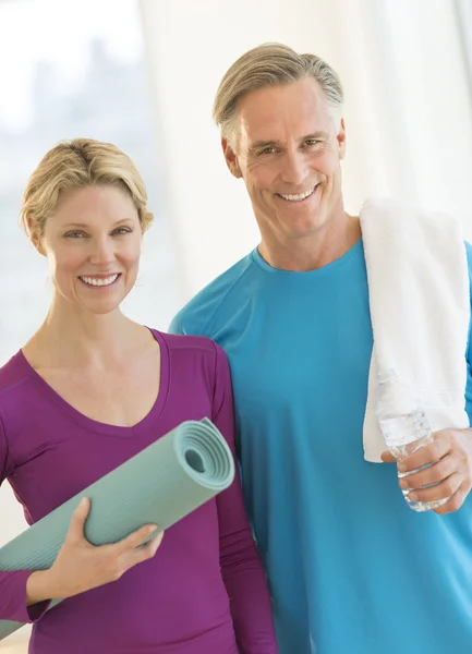 Coppia con tappetino e asciugamano per l'esercizio della bottiglia d'acqua in palestra — Foto Stock