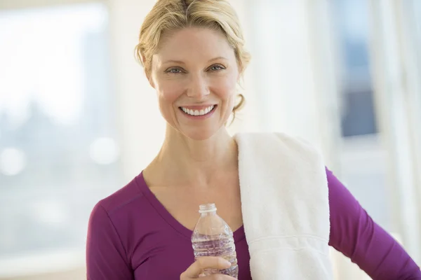 Mujer con botella de agua y toalla sonriendo en el club —  Fotos de Stock