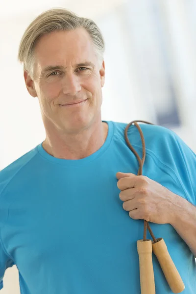 Homme confiant avec corde à sauter souriant dans la salle de gym — Photo