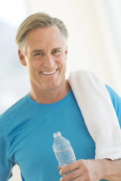 Hombre con botella de agua y toalla en el gimnasio — Foto de Stock