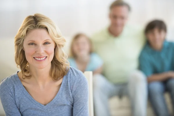 Žena s rodinou sedí na pohovce v pozadí doma — Stock fotografie