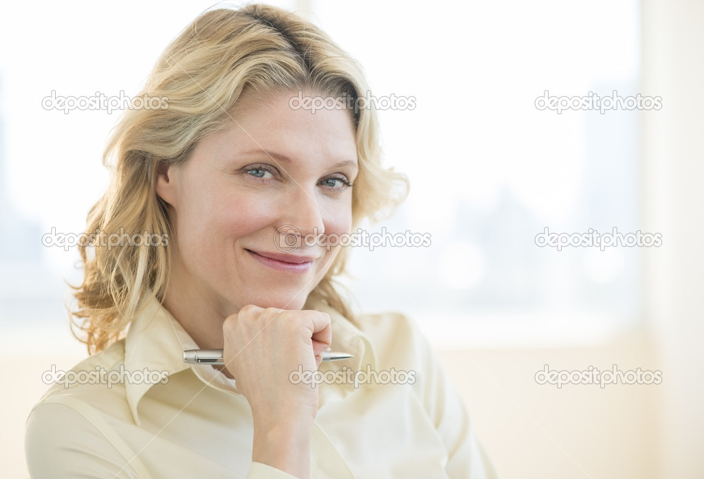 Businesswoman With Hand On Chin Smiling In Office