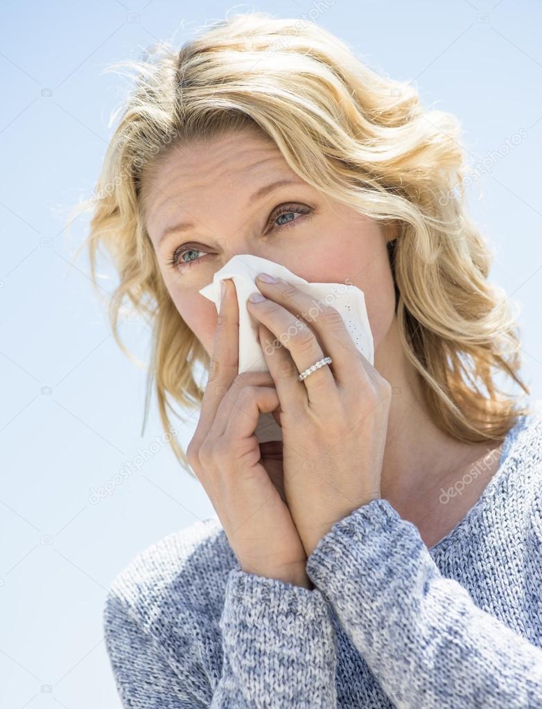 Woman Looking Away While Blowing Nose Against Clear Sky