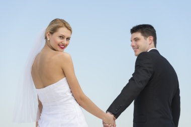 Gelin Damat'ın elini tutarak karşı açık mavi gökyüzü