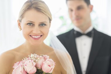 Gelin ile damat arka planda ayakta iken gül buketi