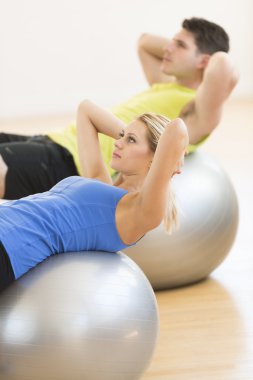 Woman Exercising On Pilate With Man In Background At Club clipart