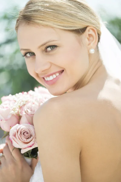 Novia en vestido de novia sin respaldo sosteniendo ramo de flores — Foto de Stock