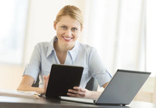 Kobieta z cyfrowego tabletu i laptopa siedząc przy biurku — Zdjęcie stockowe