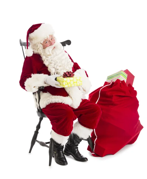 Weihnachtsmann hält Geschenkbox in der Hand, während er bei der Tasche sitzt — Stockfoto