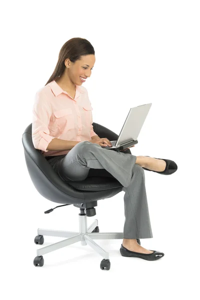 Kobieta korzysta z laptopa siedząc na krzesło — Zdjęcie stockowe