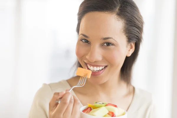 Frau isst zu Hause frischen Obstsalat — Stockfoto