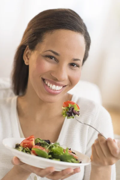 Donna felice con piatto di insalata fresca a casa — Foto Stock