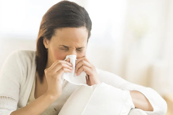 Kvinna blåser näsan med vävnad hemma — Stockfoto