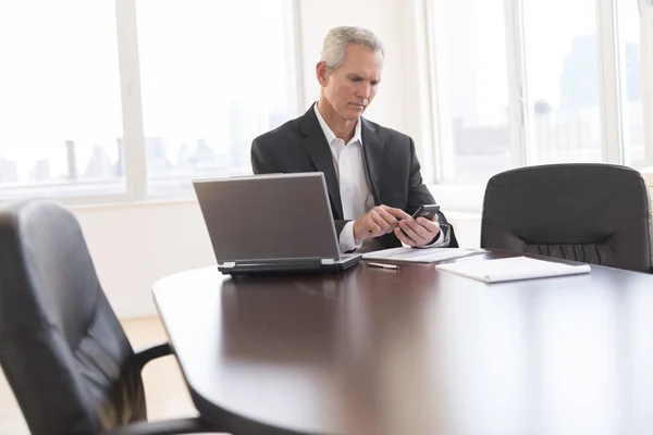 Businessman Touching Smart Phone At Desk — Stock Photo, Image