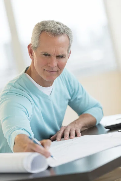 Architect schrijven op blauwdruk aan balie — Stockfoto