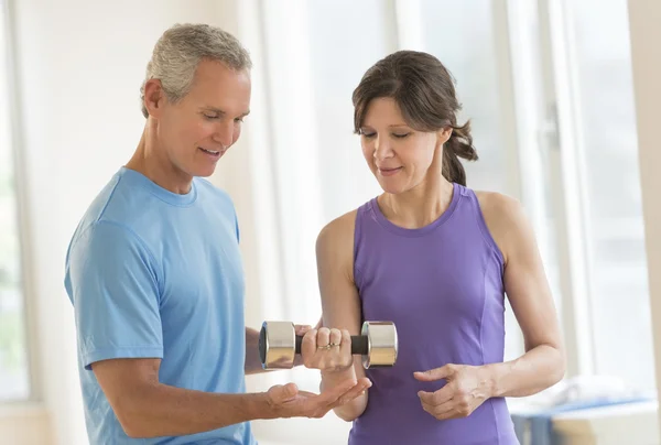 Instructor Assisting Woman In Lifting Dumbbell — Stock Photo, Image