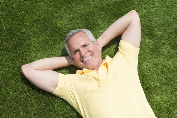 Porträt eines glücklichen Mannes, der im Gras liegt — Stockfoto