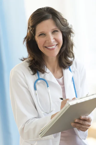 Läkaren håller Urklipp stående i kliniken — Stockfoto