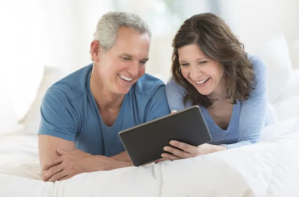 Ευτυχισμένο ζευγάρι χρησιμοποιώντας ψηφιακή δισκίο στο κρεβάτι — Φωτογραφία Αρχείου