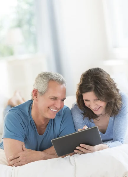 Couple utilisant une tablette numérique tout en se relaxant au lit — Photo