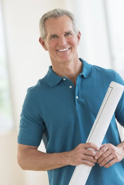 Gelukkig man bedrijf blauwdruk in nieuwe huis — Stockfoto