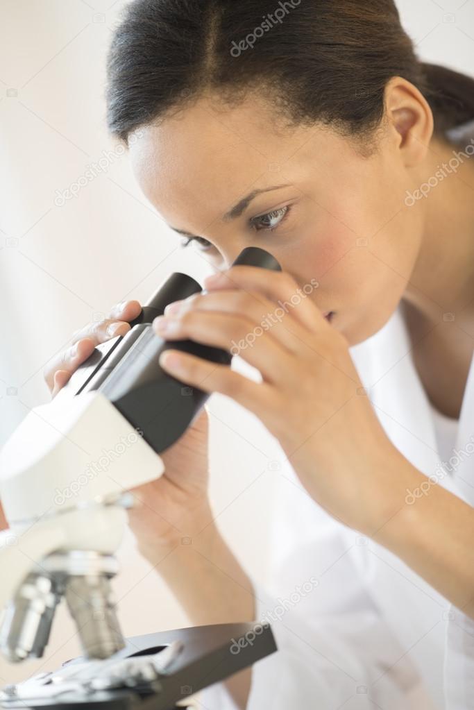 Doctor Looking Through Microscope In Laboratory