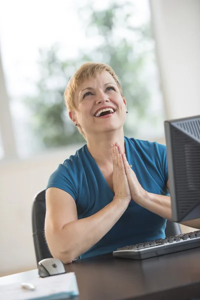 Szczęśliwa kobieta modląc się na biurku w biurze — Zdjęcie stockowe