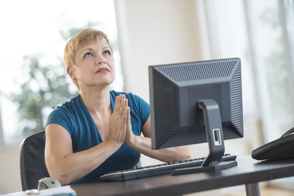 Mujer de negocios rezando mientras está sentada en el escritorio — Foto de Stock