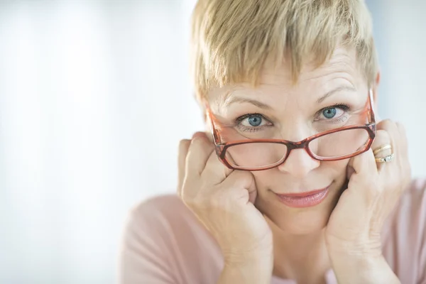 Mulher espreitando sobre seus óculos — Fotografia de Stock