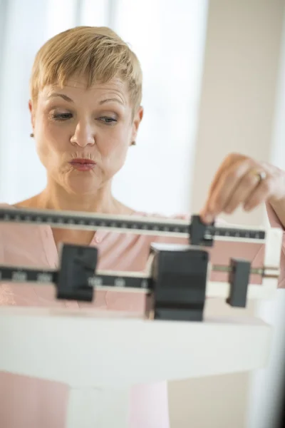 Reife Frau passt verschiebbare Gewichtswaage an — Stockfoto