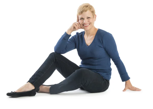 Gelukkige vrouw in casuals zittend op witte achtergrond — Stockfoto