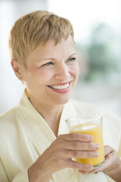 Kvinnan tittar bort medan du håller glas saft — Stockfoto