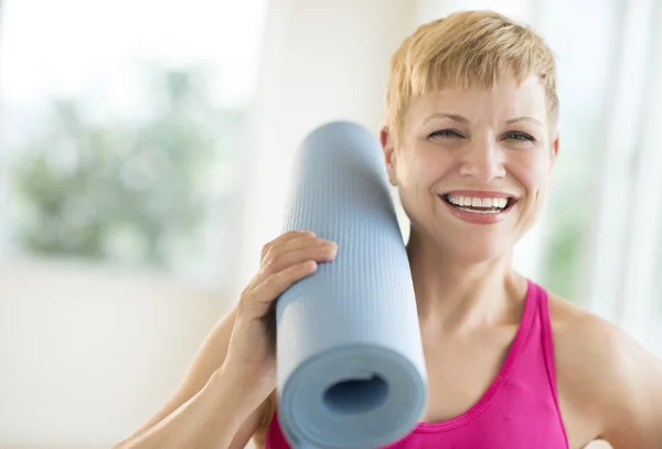 Femme joyeuse tenant roulé vers le haut tapis d'exercice — Photo