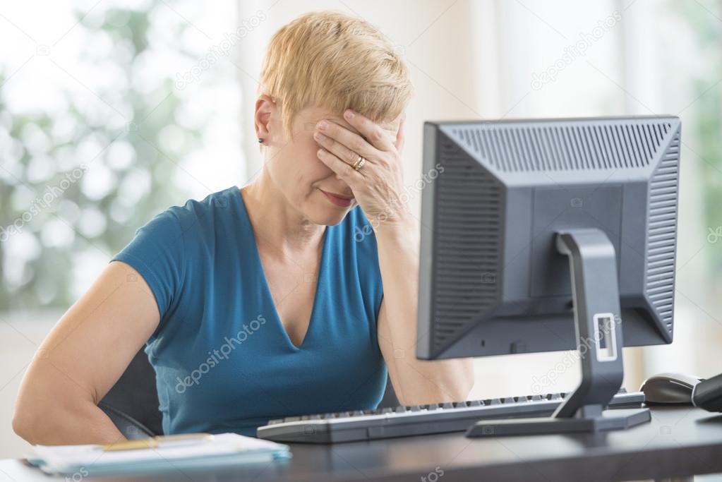 Tired Businesswoman Leaning On Computer Desk