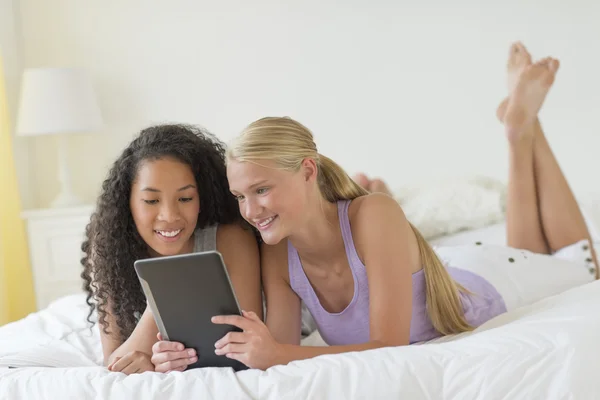 Vackra tonårsflickor med digital tablet i sängen — Stockfoto