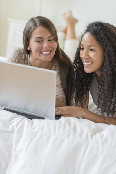 Heureuses adolescentes utilisant un ordinateur portable au lit — Photo